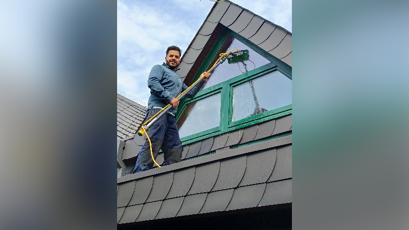 Ein Mann reinigt ein Dachfenster