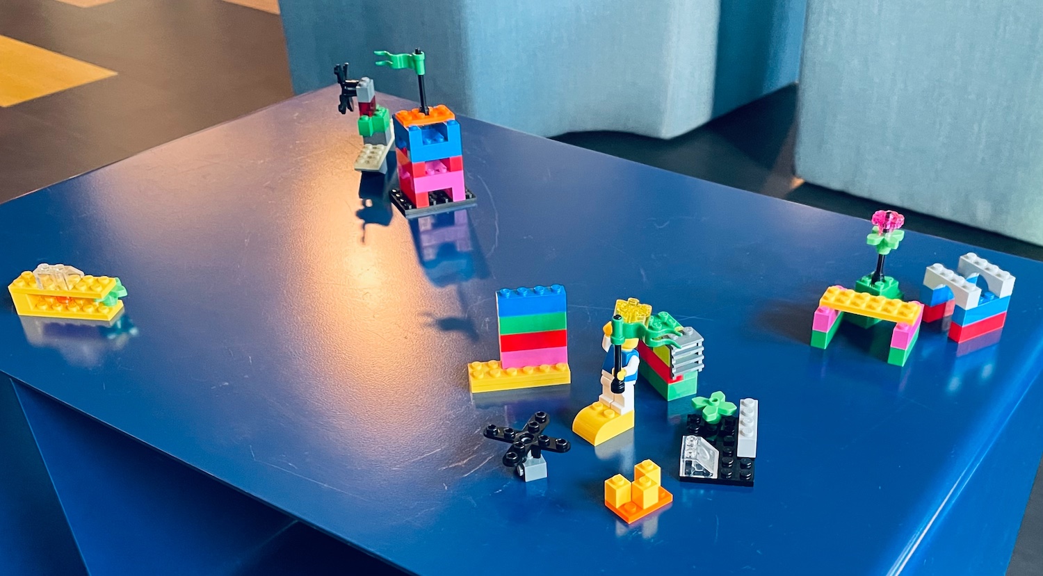 Mehrere kleine Konstruktionen aus Lego-Steinen stehen auf einem blauen Tisch